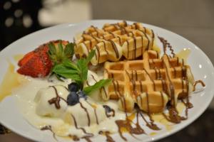a white plate with waffles and strawberries and sauce at حياة إن للأجنحة الفندقية -جده in Jeddah