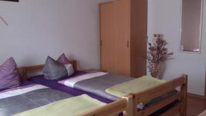 - 2 lits dans une chambre avec des oreillers violets et gris dans l'établissement Restaurant Pension Lubusch Gahro, à Gahro