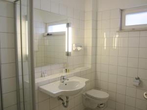een badkamer met een wastafel, een toilet en een spiegel bij Grimmelshausen Hotel in Gelnhausen