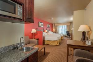 a hotel room with a bedroom with a bed and a sink at Baymont Inn & Suites by Wyndham Sturgis in Sturgis