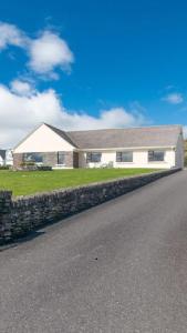 a house with a stone wall next to a road at Beachmount House in Ventry