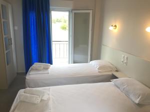 2 Betten in einem Hotelzimmer mit Fenster in der Unterkunft Seaside Apartments Flogita in Flogita