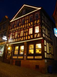 een zwart-wit gebouw met 's nachts verlichte ramen bij Grimmelshausen Hotel in Gelnhausen