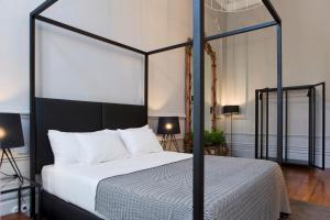 a bedroom with a black canopy bed with white pillows at Oporto Royal Apartment - Solar da Avenida in Porto