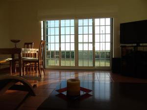 a living room with a table and chairs and large windows at Casa dos Salgueiros in Faja Grande