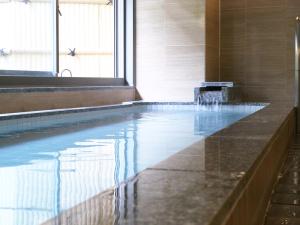 a bathroom with a swimming pool with a tub and a sink at Wisterian Life Club Atami in Atami