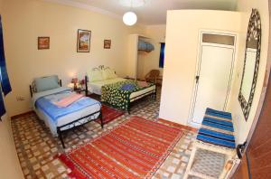 sala de estar con 2 camas y alfombra en Palmeraie Guest House, en Tinerhir
