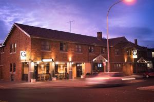 a car driving past a brick building with a street light at The George Hotel Bathurst in Bathurst
