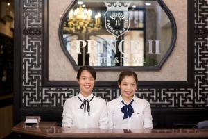 two women wearing bow ties sitting at a table at Prince II Hotel in Hanoi