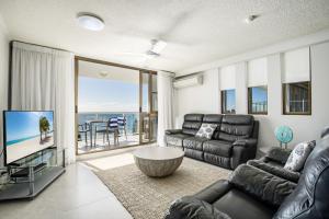a living room with a black leather couch and a television at Pacific Beach Resort in Mooloolaba