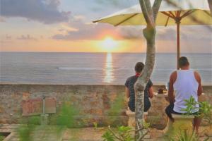 dos hombres sentados en una mesa viendo la puesta de sol en Swan Beach Inn, en Nusa Penida