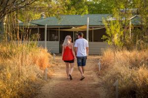 Ein Mann und eine Frau, die einen Feldweg zu einem Haus gehen in der Unterkunft Bungle Bungle Savannah Lodge in Turkey Creek