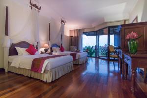 a hotel room with two beds and a desk and a balcony at Angkor Palace Suite & Villa in Siem Reap