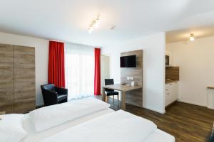 a bedroom with two beds and a desk and a table at Come IN Hotel in Ingolstadt