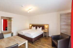 a hotel room with a bed and a table and chairs at Come IN Hotel in Ingolstadt