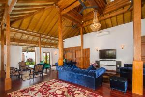 a large living room with a blue couch and a tv at Villa Joglo Jagat in Seminyak