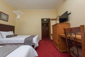 a hotel room with two beds and a desk with a television at Sunbird Mzuzu in Katoto