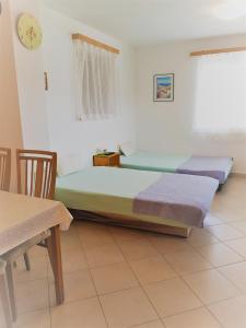 a bedroom with two beds and a table and a clock at Apartments Alicia Lopar-50m vom Strand in Lopar