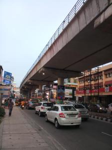 a busy city street with cars parked under an overpass at Hotel Pearl Palace in Cochin