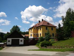 uma casa amarela numa colina com garagem em Apartmány Ilona em Rokytnice nad Jizerou