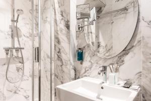 La salle de bains blanche est pourvue d'un lavabo et d'une douche. dans l'établissement Hôtel Jardin Le Bréa, à Paris