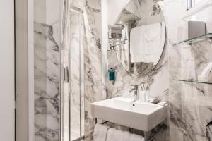 a white bathroom with a sink and a mirror at Hôtel Jardin Le Bréa in Paris