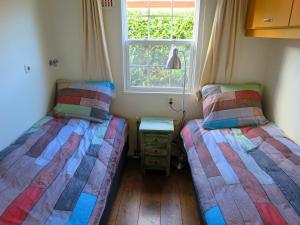two twin beds in a room with a window at dutchduochalet37 in 's-Gravenzande