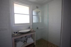 a bathroom with a sink and a glass shower at Seabreeze Hotel in Nelson Bay