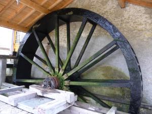 una gran rueda de madera sentada junto a una pared en Studio Manon, en Portieux