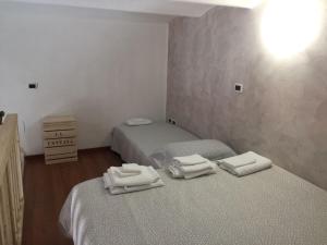 two beds in a room with white towels on them at Casa La Fontana, nel cuore dei sapori in Foggia