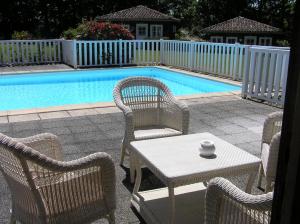 uma mesa e cadeiras em frente a uma piscina em Residences Du Golf Des Roucous em Sauveterre