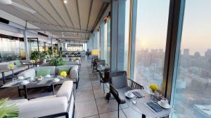 een restaurant met tafels, stoelen en ramen bij The Level at Melia Barcelona Sky in Barcelona