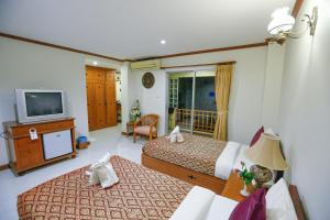 um quarto de hotel com duas camas e uma televisão em Hua Hin White Villa Hotel - SHA Certified em Hua Hin