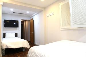 a bedroom with two beds and a tv on the wall at Charm Hotel in Seoul