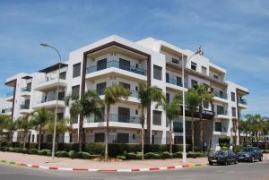 un immeuble d'appartements blanc avec des palmiers en face de celui-ci dans l'établissement Rofaida Appart'Hotel, à Agadir