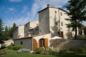 an old stone building with an umbrella in a yard at Borgo Di Pietrafitta Relais in Castellina in Chianti