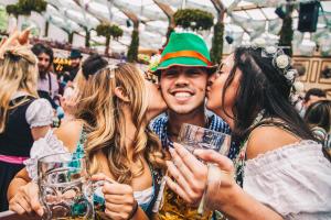 Un uomo e due donne che si baciano ad una festa di Festanation Oktoberfest Camp #2 a Monaco