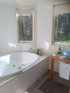 Baño blanco con bañera y lavamanos en Haven Hideaway en Berry