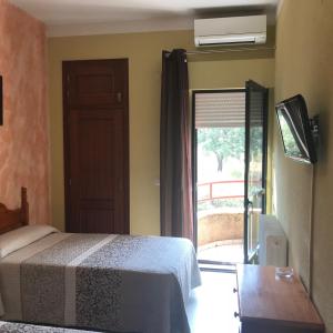 a bedroom with a bed and a door with a window at Hotel Restaurante Jarilla in Jarilla