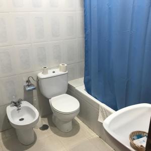 a bathroom with a toilet and a sink and a blue shower curtain at Hotel Restaurante Jarilla in Jarilla