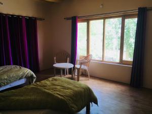 a bedroom with a bed and a table and a window at PONYO stays in Leh