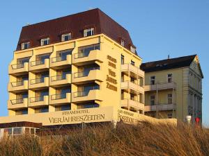 un bâtiment au sommet d'une colline à côté d'un bâtiment dans l'établissement Strandhotel VierJahresZeiten, à Borkum