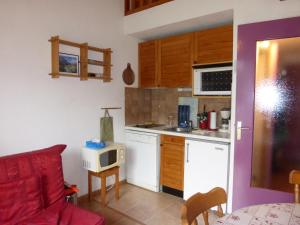 eine Küche mit einem roten Sofa und einer Mikrowelle in der Unterkunft JAUSIERS VILLAGE G 2 in Jausiers