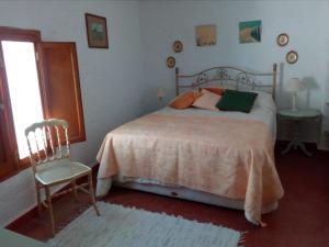a bedroom with a bed and a chair and a window at Tranquil Spanish Mountain Retreat in Benirrama