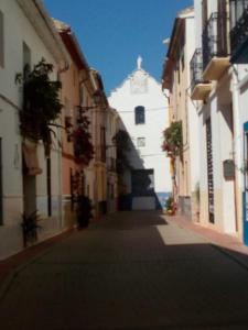 an alley with a white building with a clock tower at Tranquil Spanish Mountain Retreat in Benirrama +4 photos