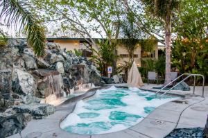 a hot tub with a waterfall in a backyard at Hotel Calle Joaquin - San Luis Obispo in San Luis Obispo