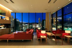 広島市にあるカンデオホテルズ 広島 八丁堀の赤い家具付きのリビングルームが備わり、市街の景色を望めます。