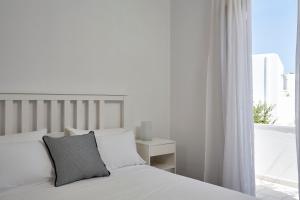 una camera bianca con un letto e una finestra di Sunrise Paros a Naoussa