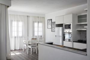 a kitchen with white cabinets and a table with chairs at Sunrise Paros in Naousa