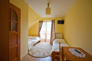 1 dormitorio con 2 camas, mesa y ventana en Wynajem pokoi Natalia, en Sromowce Niżne